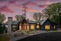 living-stone-–-daydream-rustic-modern-–-high-hickory-–-swannanoa-nc-–-custom-home-build-–-twilight-exterior-stone-chimney-–-03